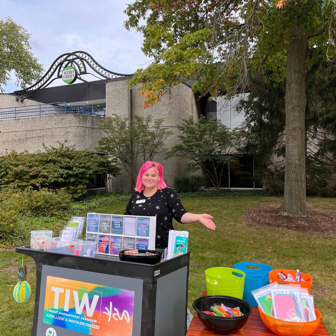 WIT peer educator standing behind the WIT cart near Fresh Food co. dining hall